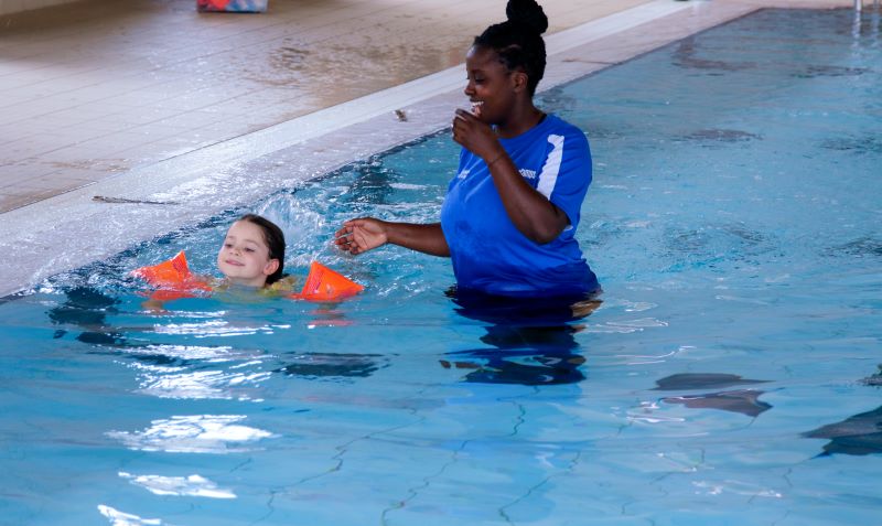 child and staff member in pool